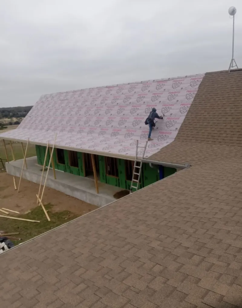 Worker preparing underlayment for a metal roof installation in Exeter